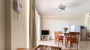 Ein Zimmer mit Fußballtisch, Fernseher, Deckenventilator und einer Küchenzeile inklusive Kühlschrank und Mikrowelle.