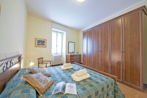 Une chambre à coucher comprenant un lit, une armoire, une commode, une chaise et une fenêtre.
