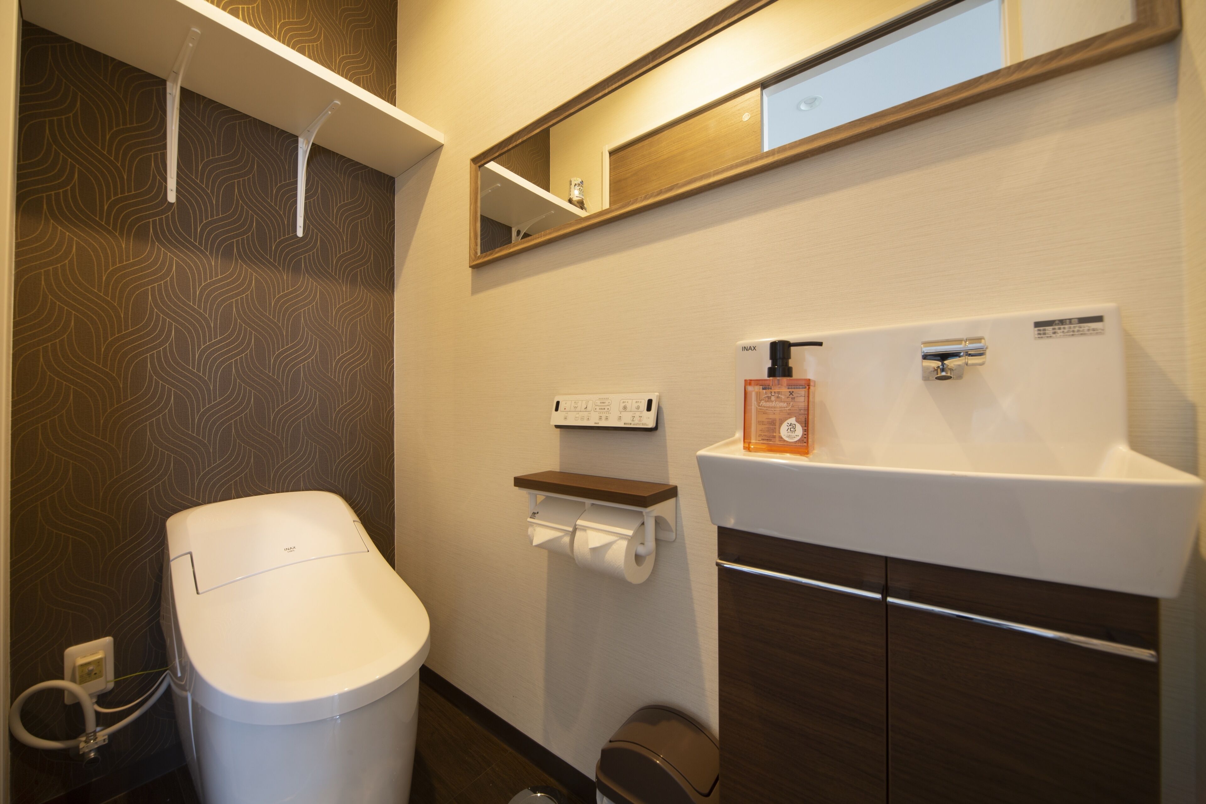 A modern bathroom with a toilet, a sink, a mirror, and a toilet paper holder.