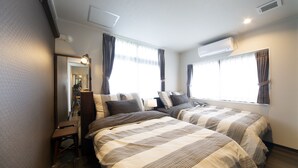 Een hotelkamer met twee bedden, een bureau, een spiegel en een raam met gordijnen.