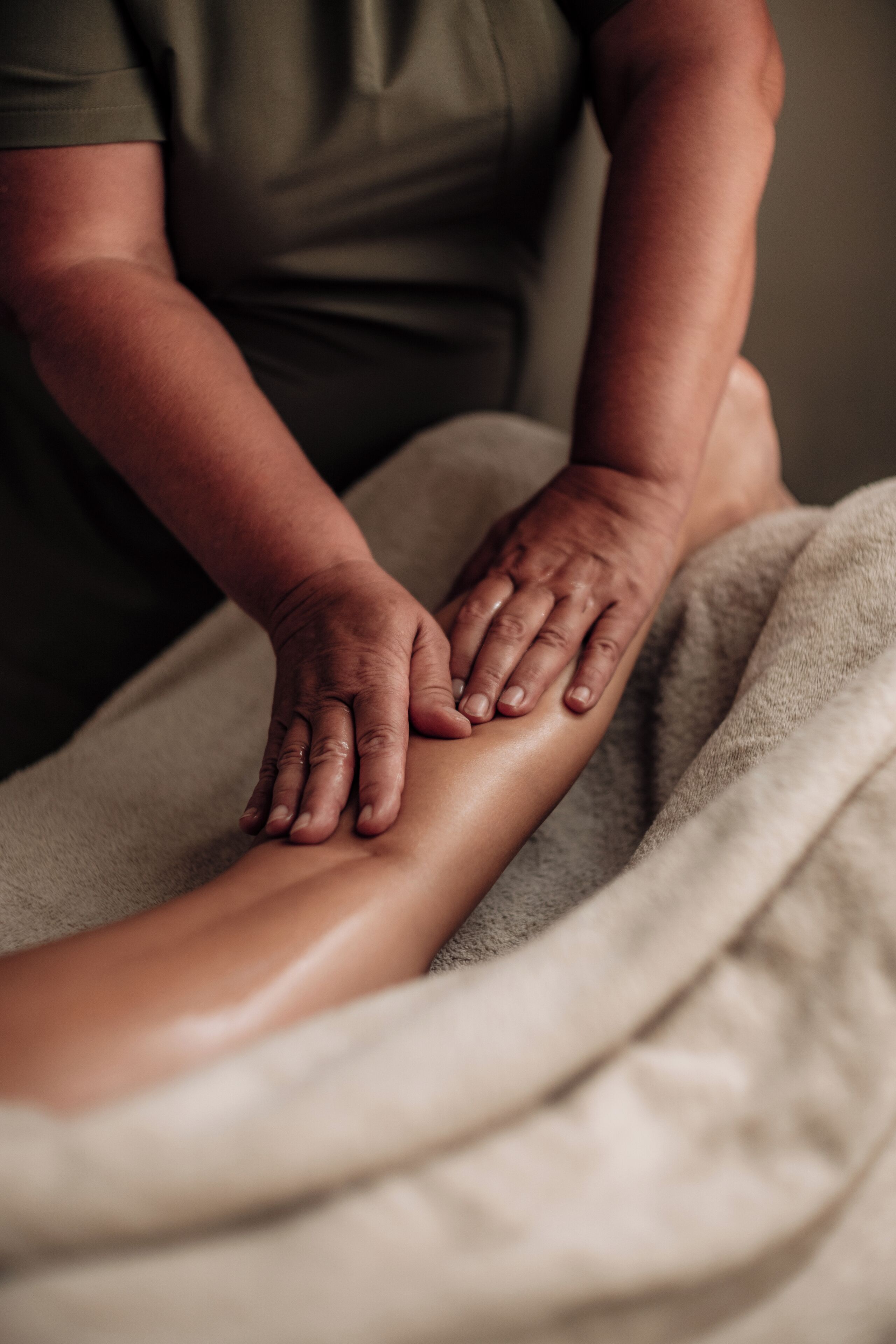 Nahaufnahme von Händen, die eine Beinmassage geben.