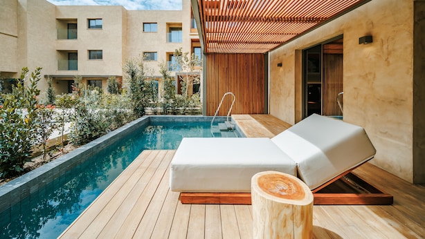 A modern outdoor pool area with a wooden deck, a lounge chair, and a wooden pergola. - M Boutique Hotel - Designed for Adults (Paphos)