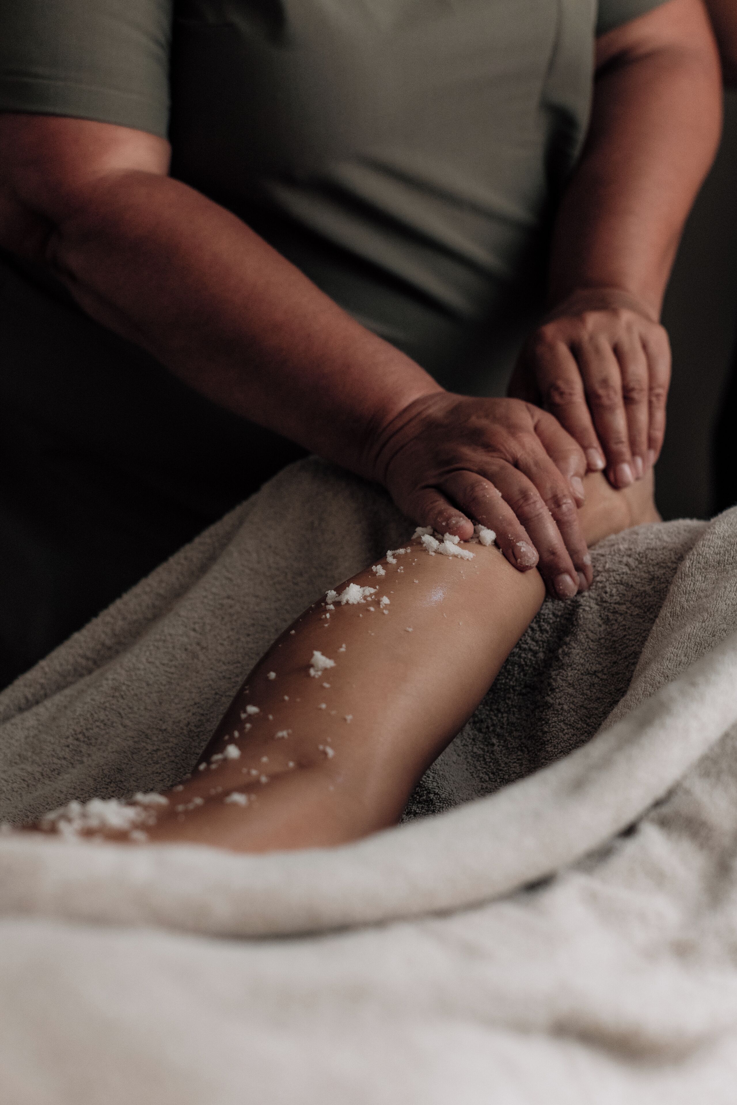 A person receiving a massage with a towel covering the lower body.