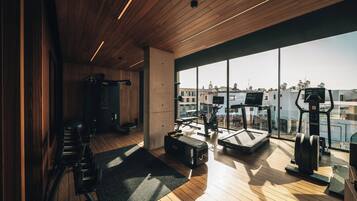 Un gimnasio con equipo de ejercicio, ventanas amplias y techo de madera.