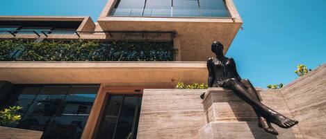 A modern building with a large glass window and a bronze statue of a seated figure.