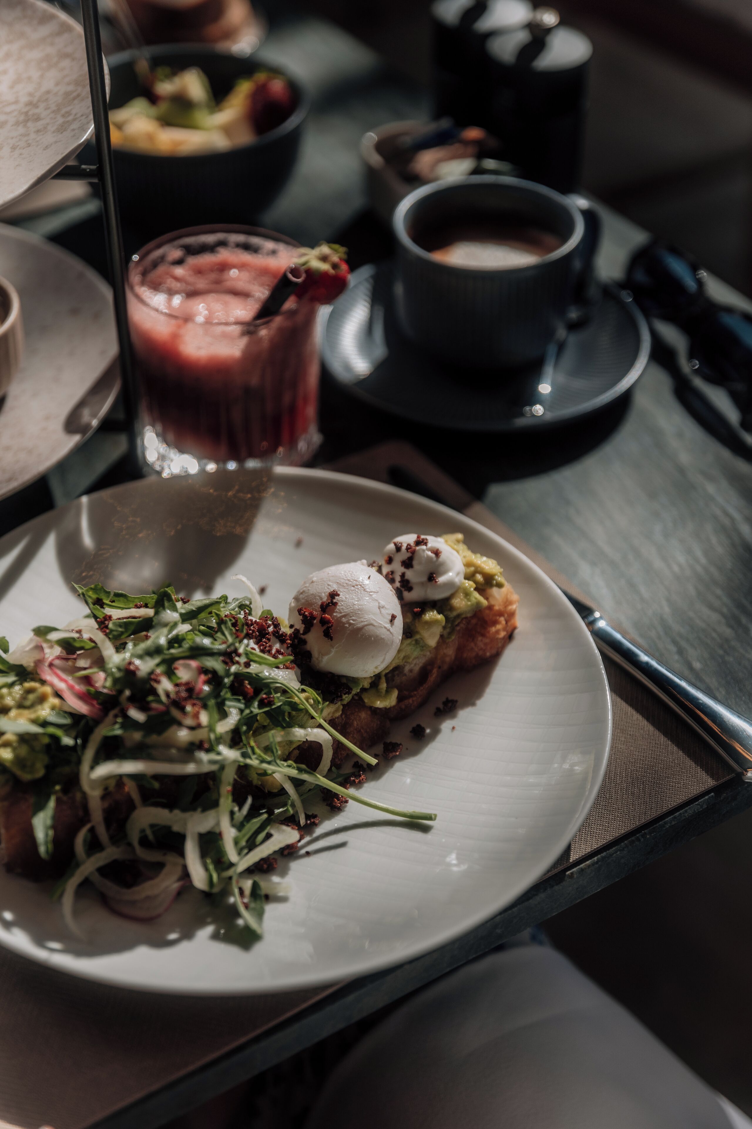 Une table à manger avec une assiette de nourriture, un verre de boisson et une tasse de café.
