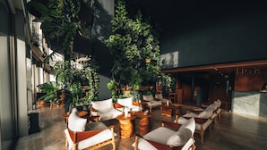 A spacious indoor area with wooden flooring, multiple seating arrangements, and various potted plants. - M Boutique Hotel - Designed for Adults (Paphos)