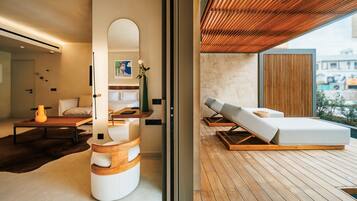 Un interior moderno con una zona de estar que incluye techo de madera, un espejo grande y un espacio con cojines.