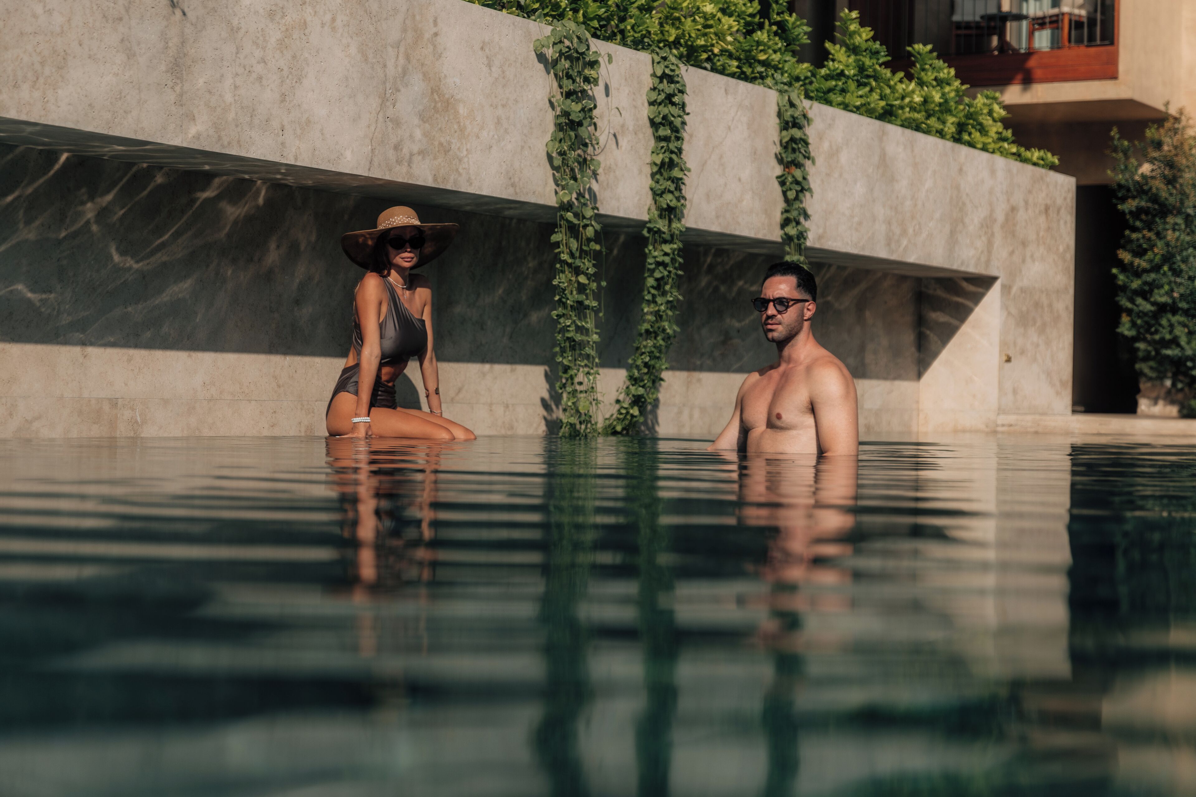 Une piscine avec un mur en béton et de la végétation.