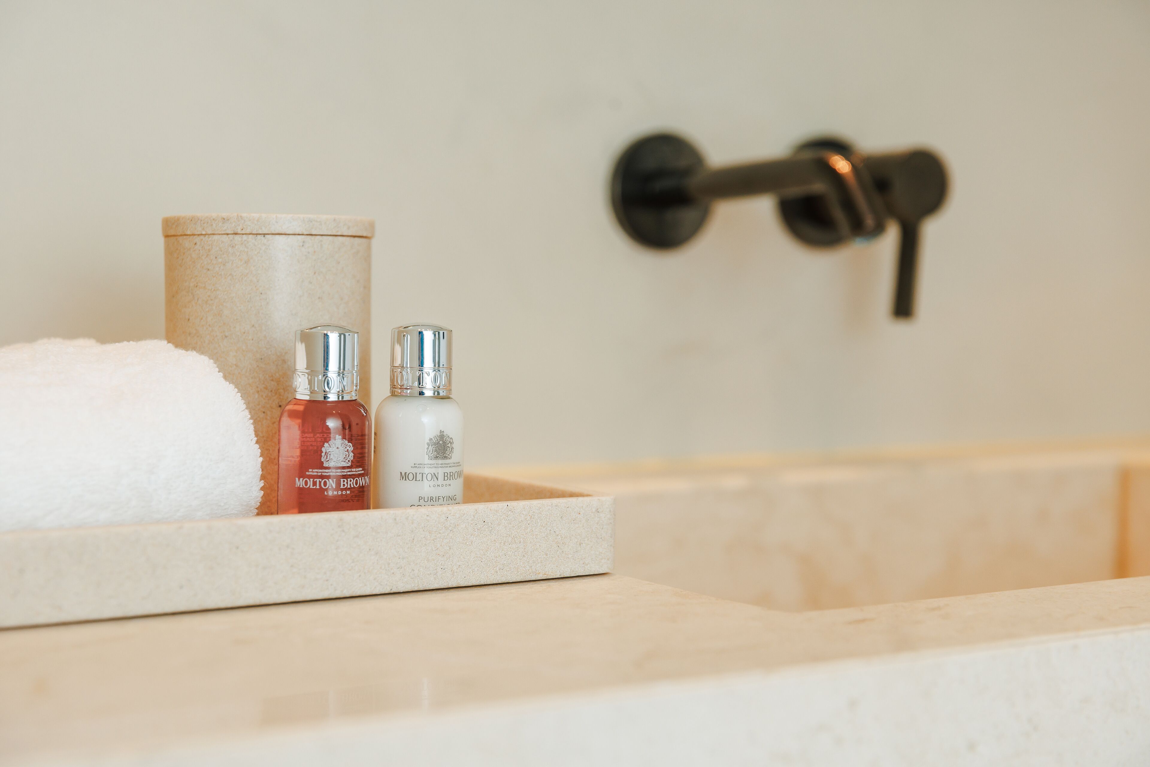Une salle de bain avec une baignoire, une serviette et deux flacons de produits de toilette.