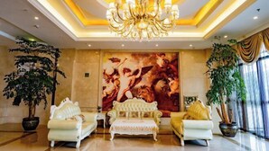 A lobby with a chandelier, two sofas, a large painting, and potted plants. - Vienna International Hotel (Liupanshui Shuicheng) (Liupanshui)