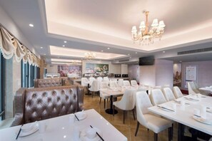 A restaurant with white table settings, a chandelier, and a large window with curtains. - Vienna International Hotel (Liupanshui Shuicheng) (Liupanshui)