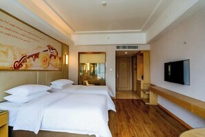 A hotel room with two beds, a flat-screen TV, wooden flooring, and a large painting on the wall. - Vienna International Hotel (Liupanshui Shuicheng) (Liupanshui)