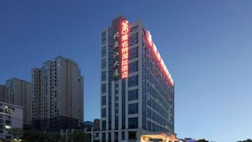 A multi-story hotel building with illuminated signage, surrounded by other high-rise buildings.