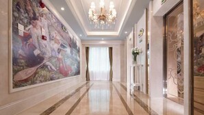 A hallway with a large mural, a chandelier, and a glass door with decorative elements. - Vienna International Hotel (Liupanshui Shuicheng) (Liupanshui)
