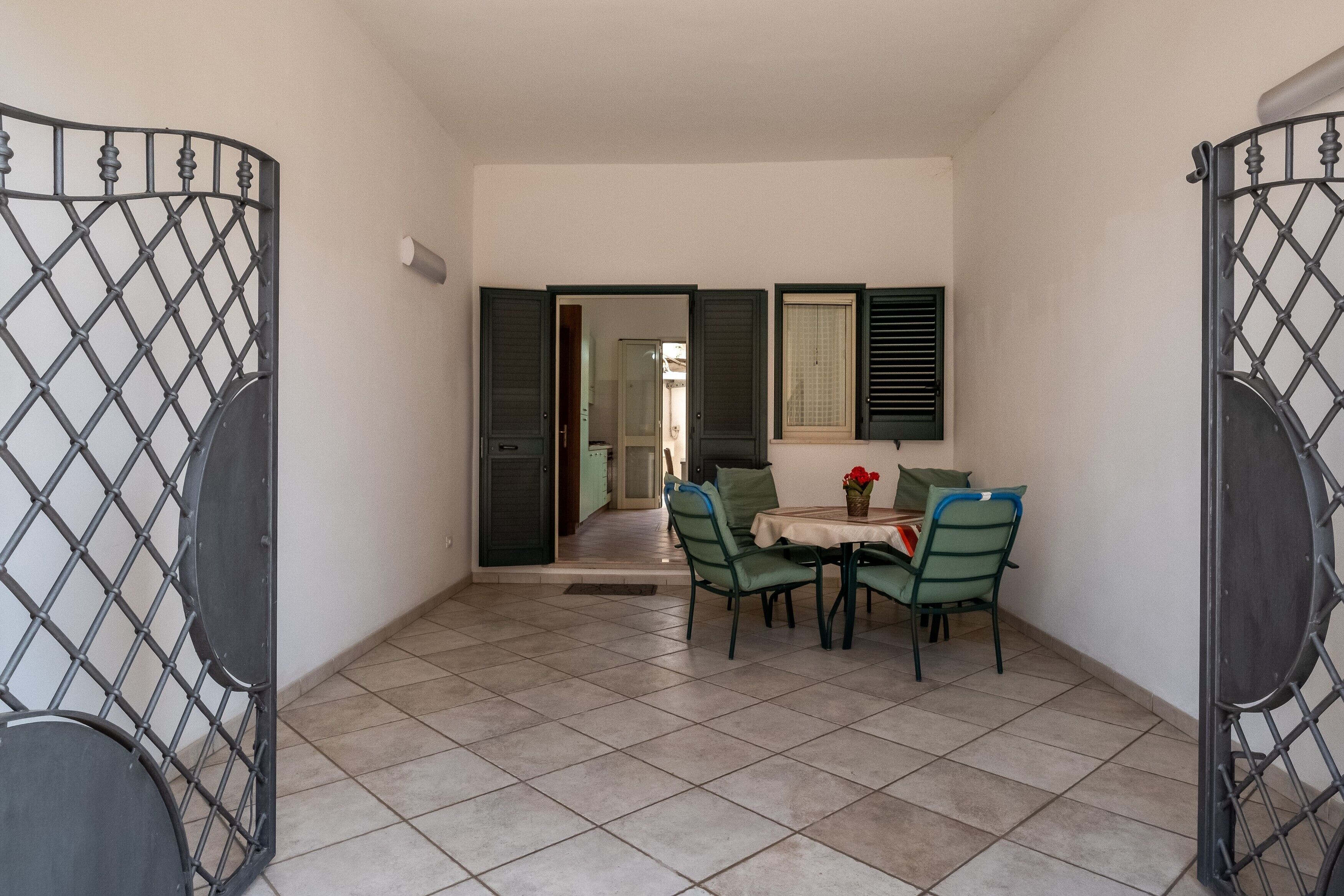 A room with a tiled floor, a table with chairs, and a door with a metal gate.