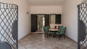 A room with a tiled floor, a table with chairs, and a door with a metal gate.
