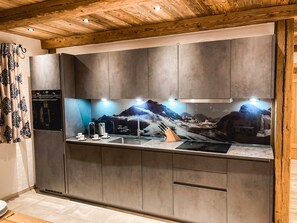 Een moderne keuken met grijze kastjes, een roestvrijstalen spoelbak en een spatwand met bergmotief.