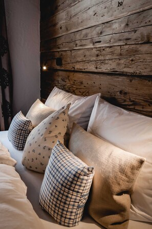 Een bed met veel kussens tegen een houten wand.