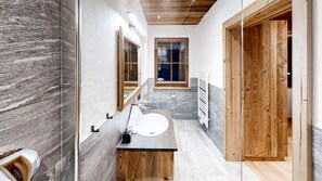 A modern bathroom with a wooden vanity, a large mirror, and a window above the sink. - Stadl-suite Silvretta - Stadl Chalet Ischgl (Ischgl)