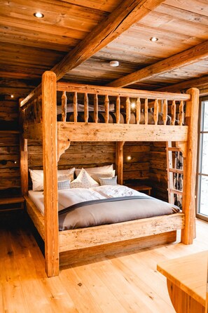Ein Holzbett mit zwei Etagen, eine Holztreppe, ein Tisch und ein Fenster mit Vorhängen.