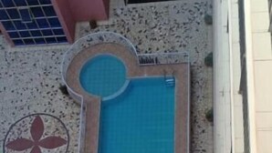 Un espace piscine aménagé sur le toit, comprenant une piscine rectangulaire, un jacuzzi circulaire et un décor de mosaïques.