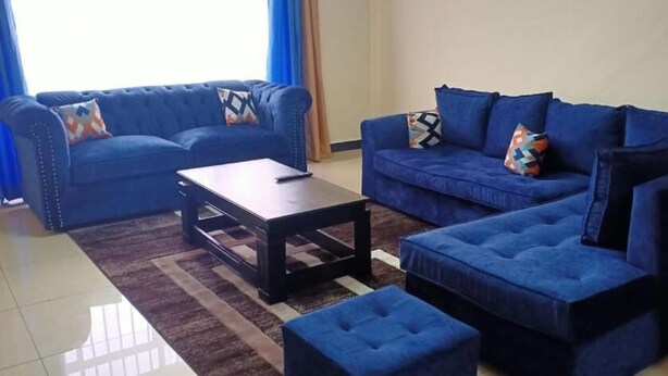 Un salon avec deux canapés bleus, une table basse et un pouf.