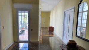 Un pasillo con suelo pulido, una puerta que da al exterior y una pequeña mesa con un adorno.