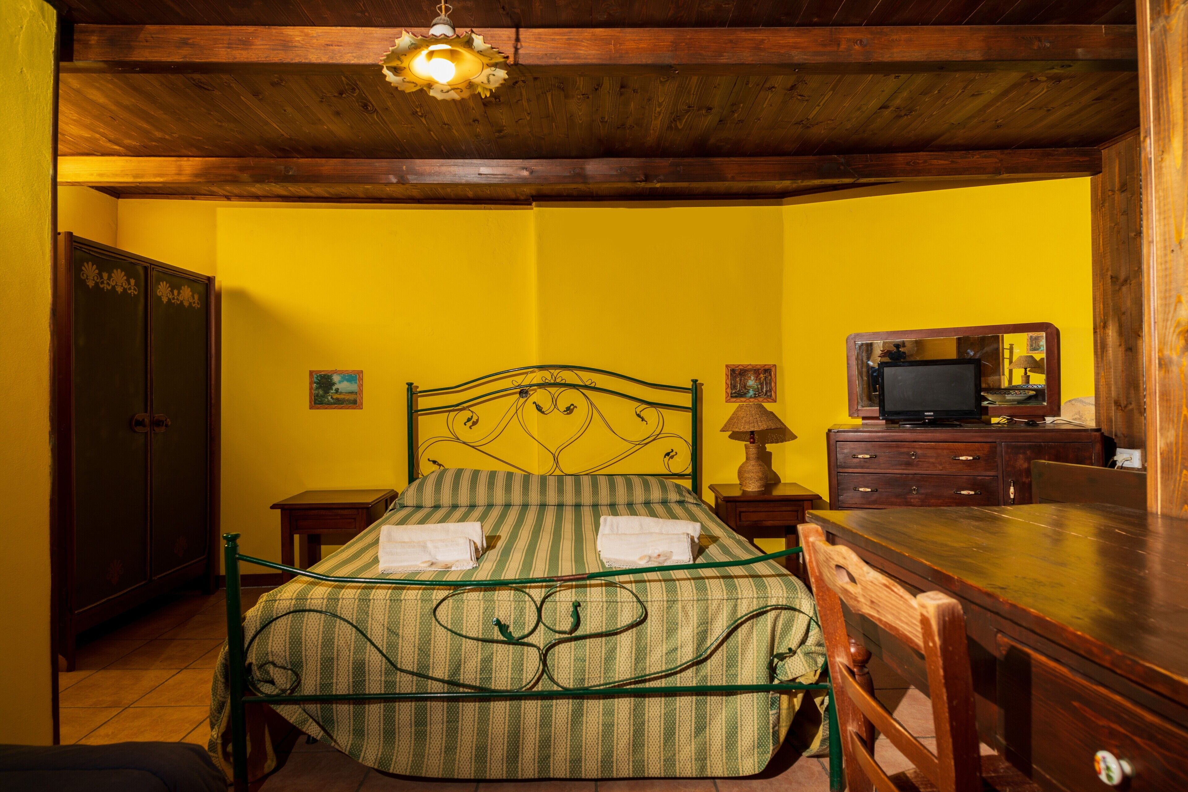 Une chambre avec un lit, des meubles en bois, une télévision et un miroir.