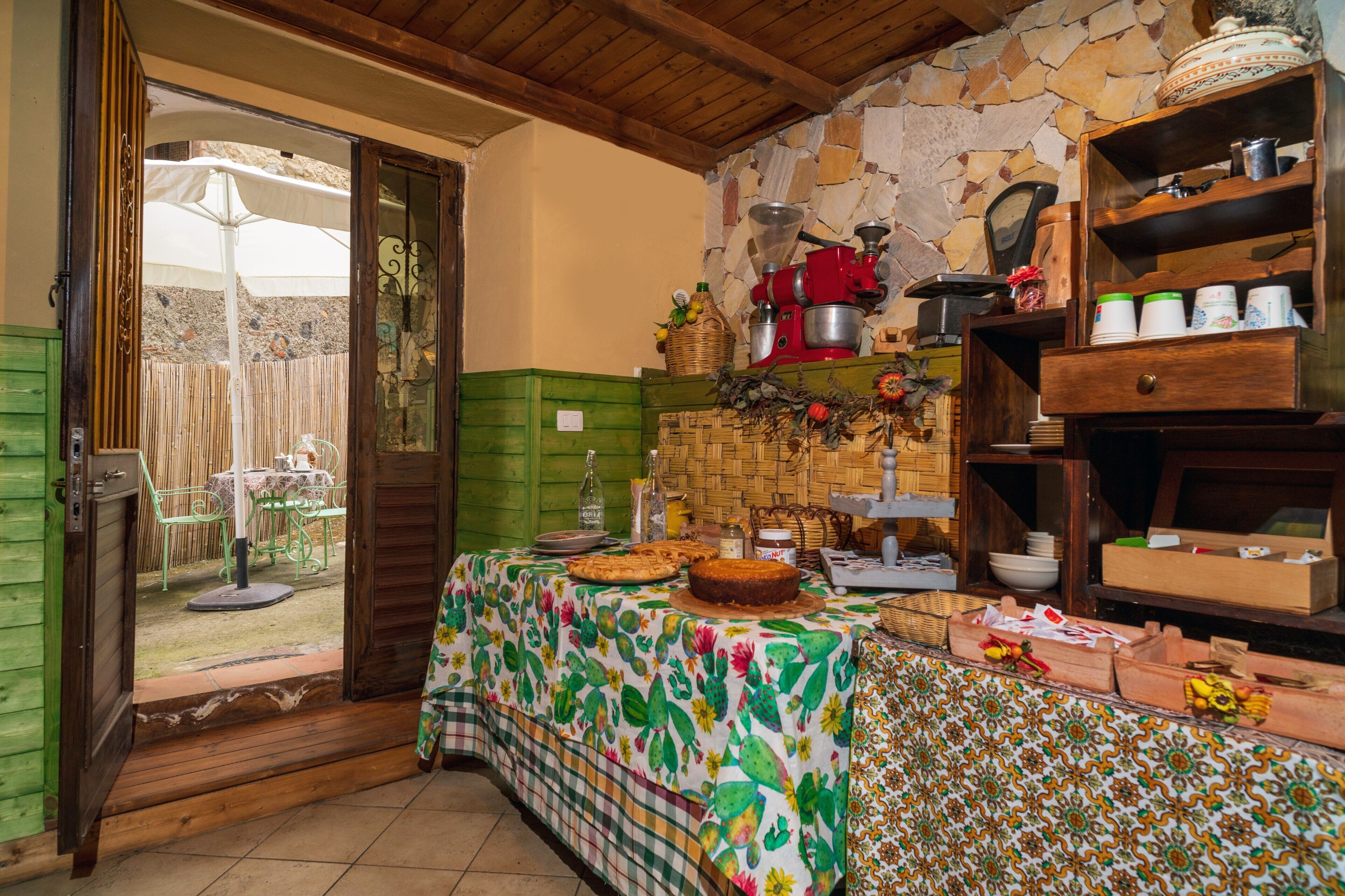 Una cucina con un tavolo apparecchiato per mangiare, un muro in pietra e un soffitto in legno.