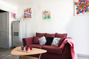 Una sala de estar con un sofá rojo, una mesita y tres cuadros en la pared.