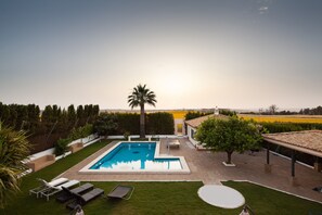 Une piscine avec des chaises longues, un palmier et une vue sur la campagne.