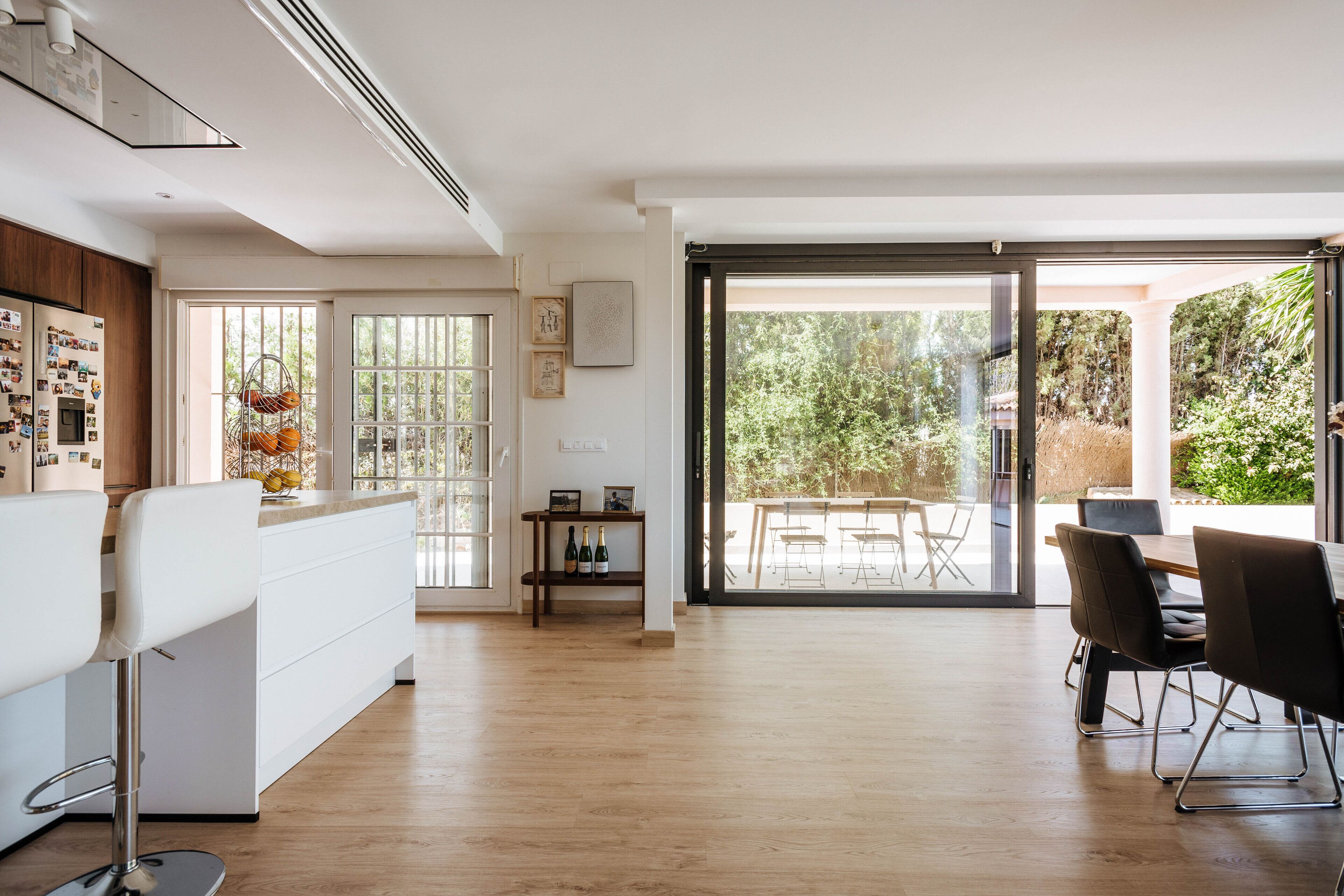 Eine moderne Küche mit einem weißen Kühlschrank, Holzschränken und einem Essbereich mit Tisch und Stühlen.