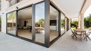 Una casa moderna con un portón de vidrio corredizo que da a un patio con una mesa y sillas.