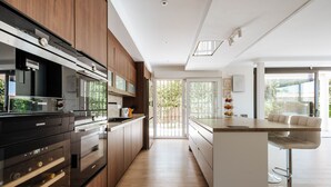 Una cocina moderna con armarios de madera, horno empotrado y una zona de bar con taburetes.