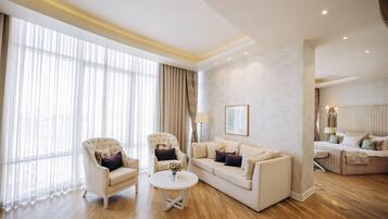 A spacious living room with a large window, a sofa set, a coffee table, and a separate seating area with a lamp.