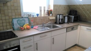 A kitchen with a dishwasher, oven, and a window with a view.