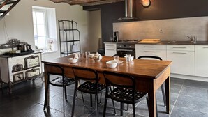 Une cuisine moderne avec une table en bois, des chaises noires et un plafond en briques.