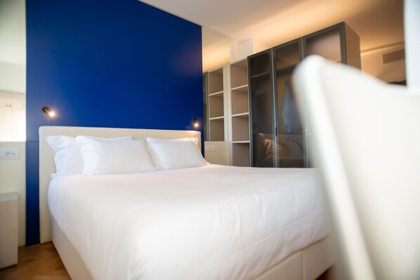 A modern hotel room with a large bed, a wardrobe, and a nightstand. - Padova Suites C20 (Padova)