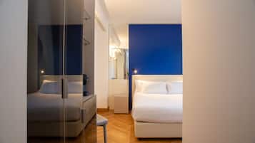 Una habitación de hotel moderna con un separador de vidrio, una cama, una mesita de noche y una lámpara de noche.