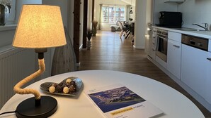 Una cucina moderna con mobili bianchi, un'area pranzo con un tavolo apparecchiato per due e vista sul soggiorno.