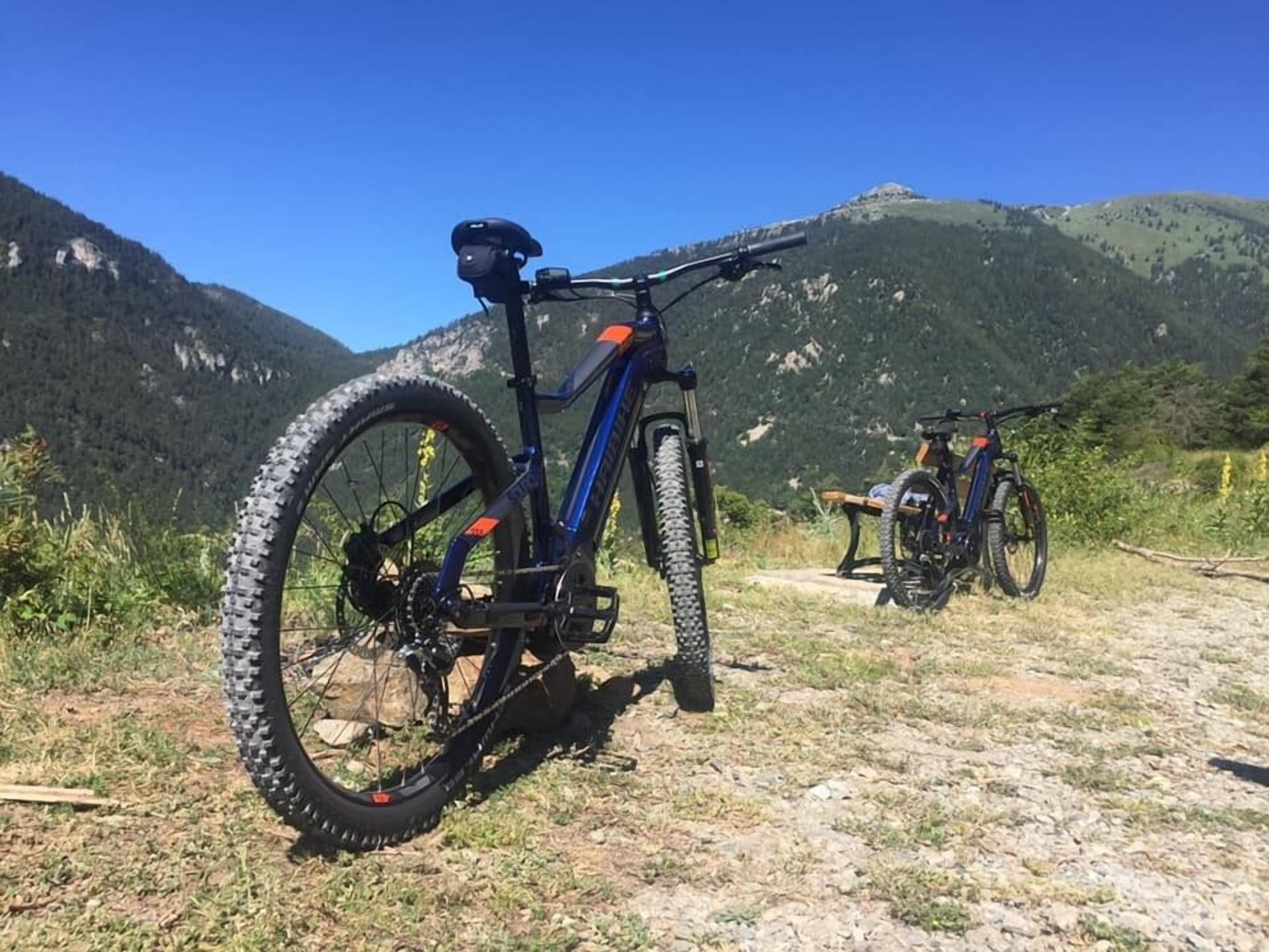 A mountain bike parked on a gravel path with a mountainous backdrop.
