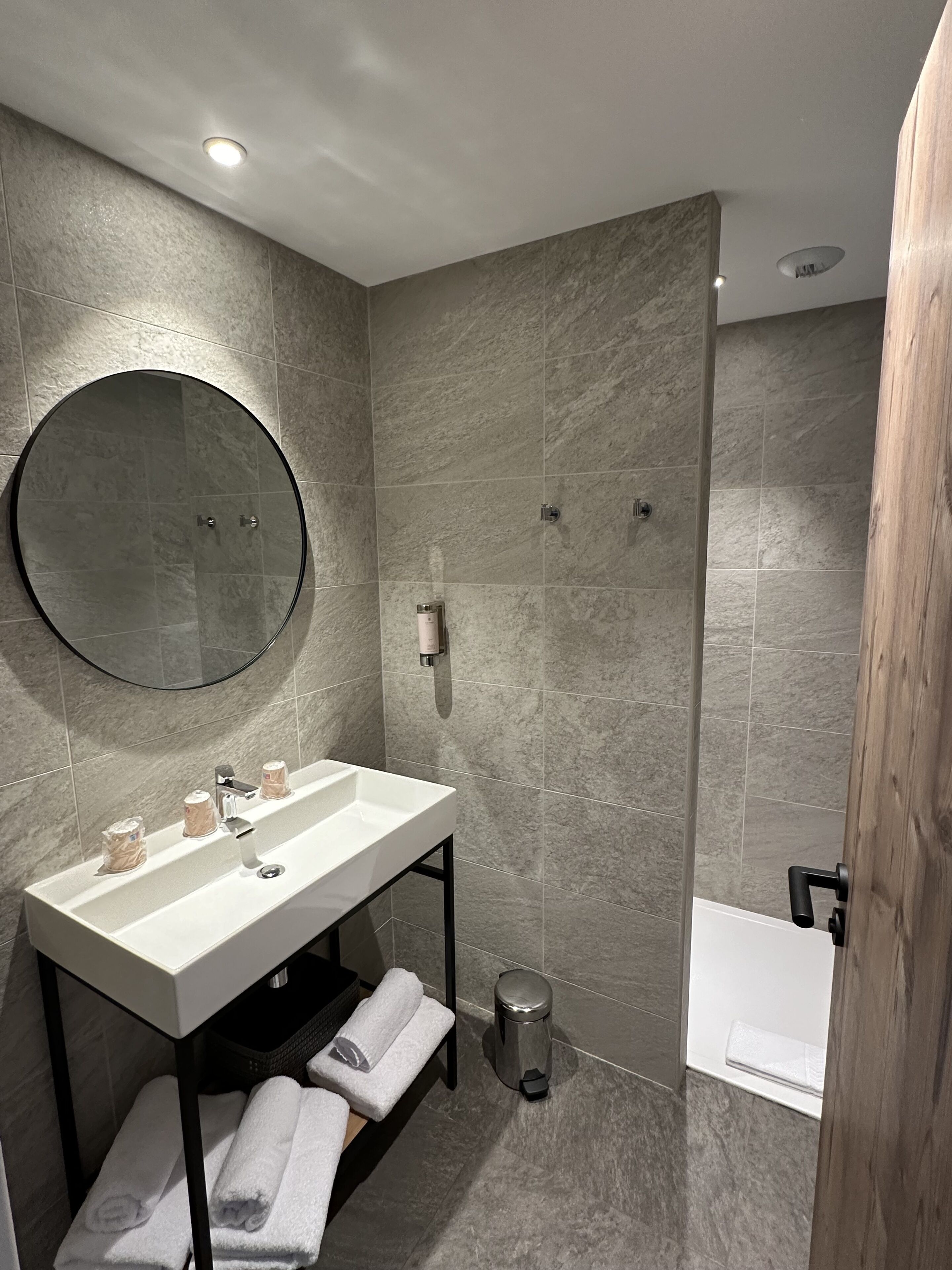 A modern bathroom with a white sink, mirror, and shower.