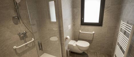 A modern bathroom with a glass-enclosed shower, a toilet, and a window.