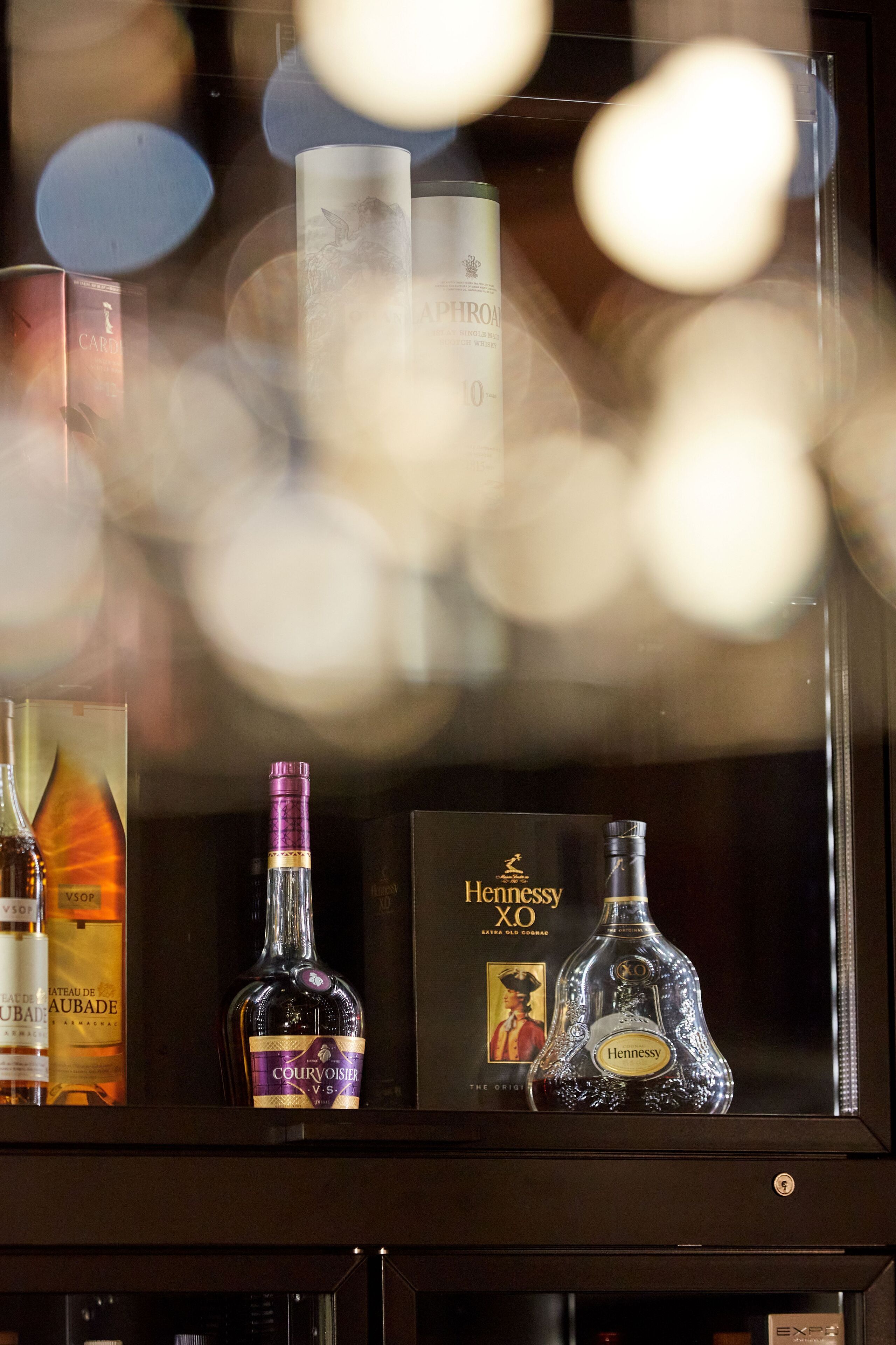 A display of liquor bottles, including Courvoisier and Hennessy, in a glass case.