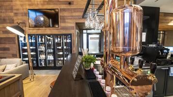 Un espace bar doté d’un système de robinets à bière en cuivre, d’un comptoir et d’un coin salon avec un canapé et un téléviseur.