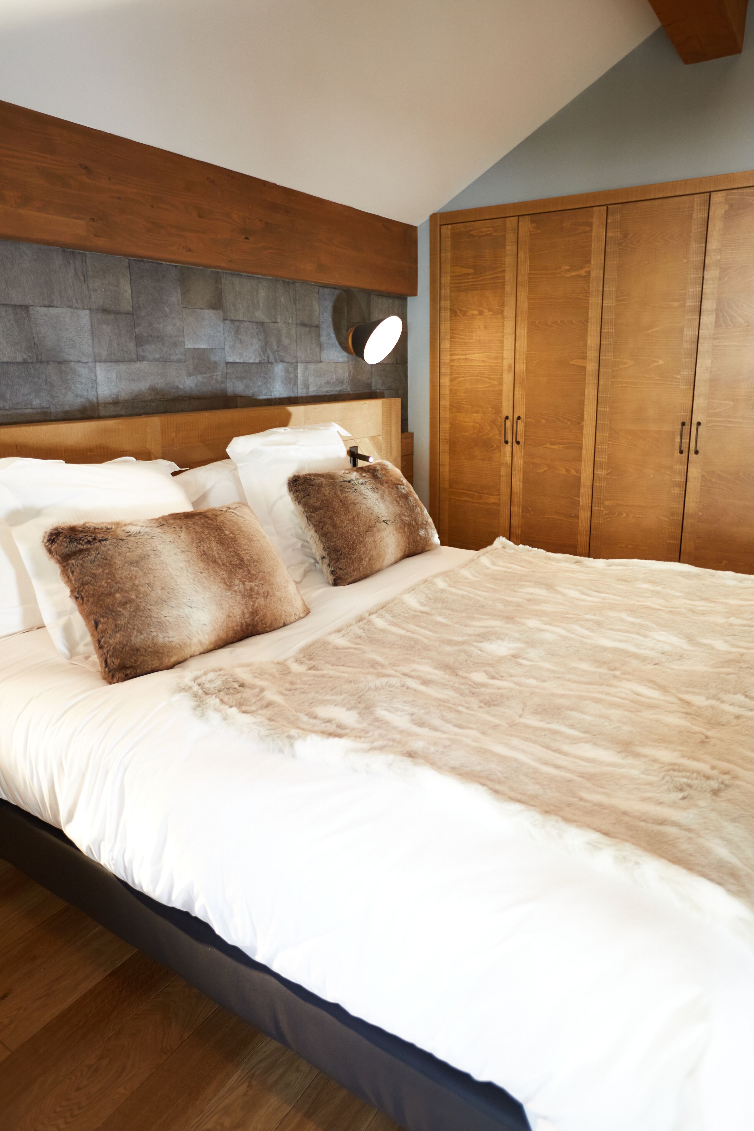 A bedroom with a large bed, wooden headboard, and a wardrobe.