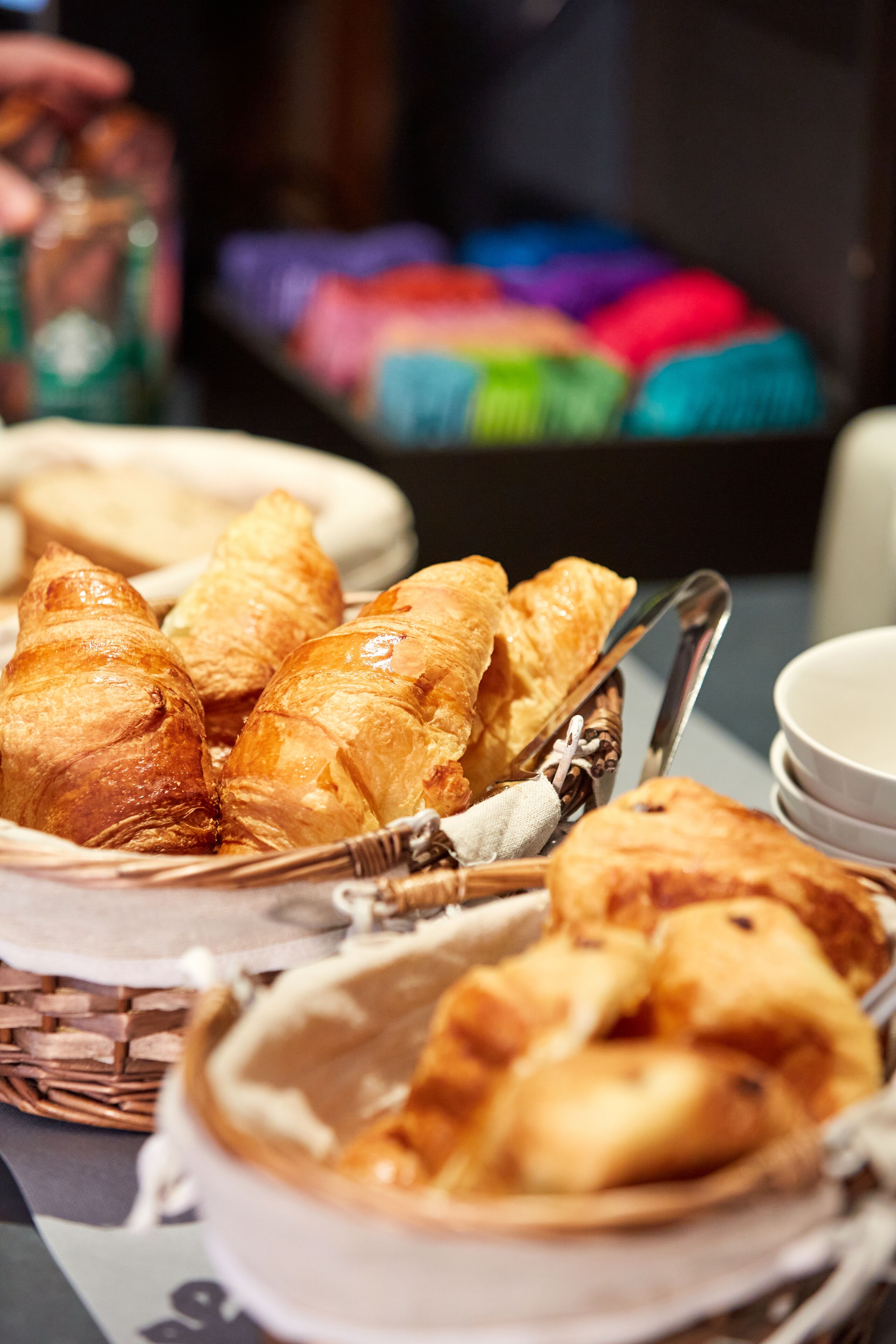 A basket of croissants and a bowl of soup on a table.