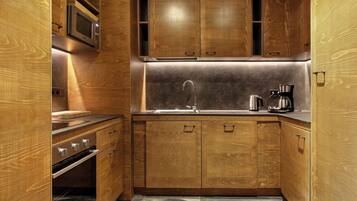 A compact kitchen with wooden cabinets, a stainless steel oven, a microwave, and a coffee maker.