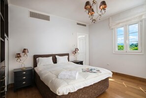 A bedroom with a bed, nightstands, lamps, a window, and a door.